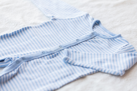 baby clothes, babyhood, motherhood and object concept - close up of blue bodysuit on towel for newborn boyの写真素材