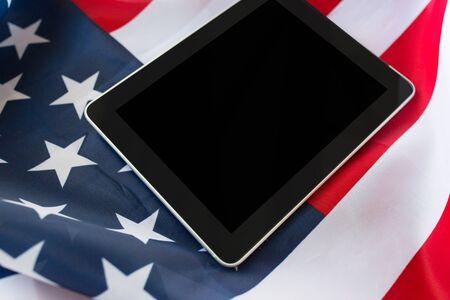 technology, american independence day, patriotism and nationalism concept - close up of tablet pc computer on american flagの写真素材