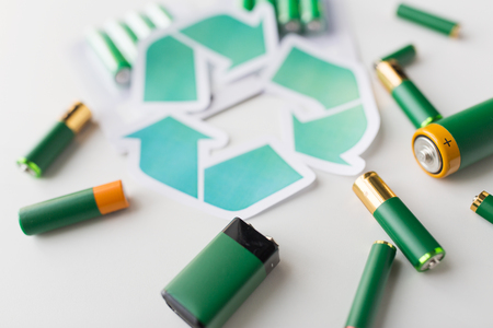 waste recycling, garbage disposal, environment and ecology concept - close up of used alkaline batteries and green recycling symbolの写真素材