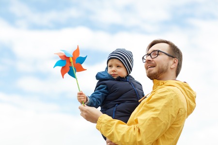 family, childhood, fatherhood, leisure and people concept - happy father and little son with pinwheel toy outdoorsの写真素材