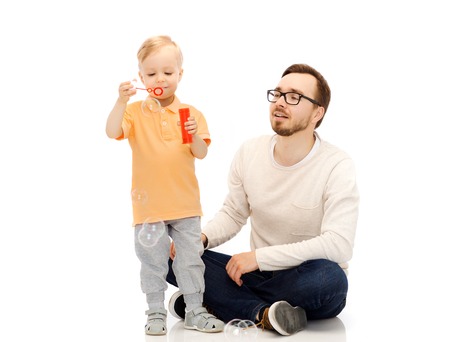 family, childhood, fatherhood, leisure and people concept - happy father and little son blowing bubbles and having funの写真素材