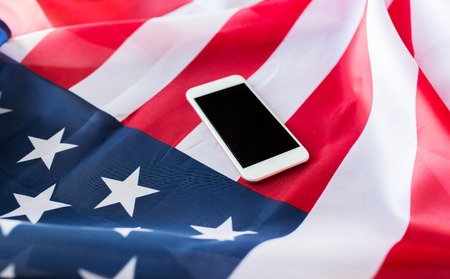 technology, american independence day, patriotism and nationalism concept - close up of smartphone with black blank screen on american flagの写真素材