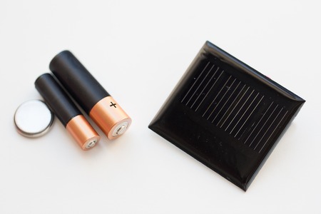 recycling, energy, power, environment and ecology concept - close up of alkaline batteries and solar...