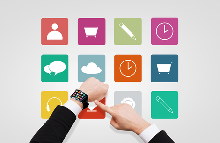 business, multimedia, people and modern technology concept - close up of businessman hand pointing to smart watch with menu icons on screenの写真素材
