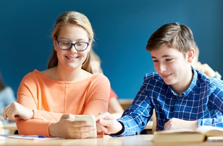 education, learning, technology, communication and people concept - students with smartphone texting...