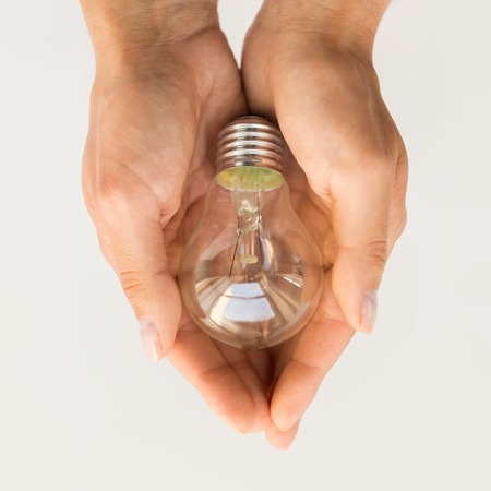 recycling, electricity, environment and ecology concept - close up of hands holding lightbulb or incandescent lampの写真素材