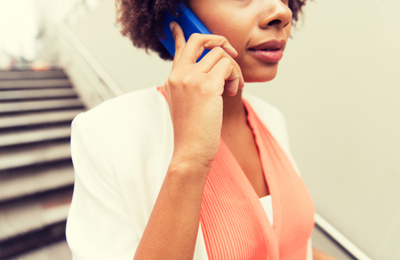 business, communication, technology and people concept - close up of african woman calling on smartphone walking downstairs to city subwayの写真素材