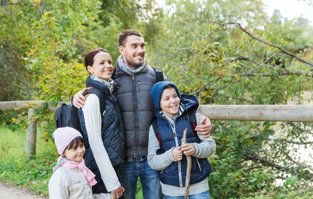 adventure, travel, tourism, hike and people concept - happy family walking with backpacks in woods