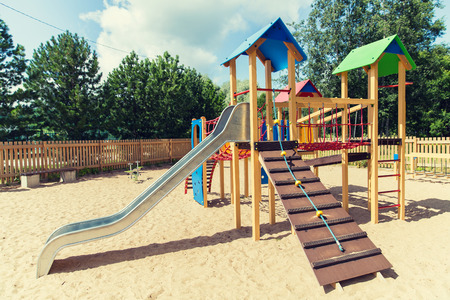 childhood, equipment and object concept - climbing frame with slide on playground outdoors at summer