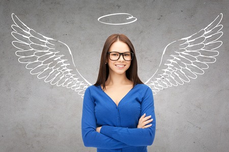 business, angel investor, safety, security and people concept - smiling young businesswoman with wings and nimbus drawing over gray concrete backgroundの写真素材