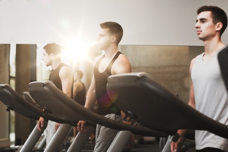 sport, fitness, lifestyle, technology and people concept - group of men exercising on treadmill in gymの写真素材