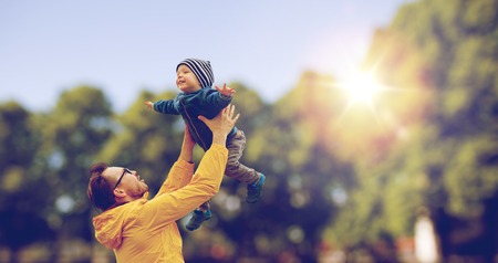 family, childhood, fatherhood, leisure and people concept - happy father and little son playing and having fun outdoors over summer park backgroundの写真素材