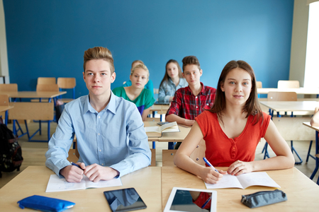 education, learning and people concept - group of students with notebooks and tablet pc computers at...