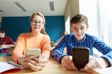 education, learning, technology, communication and people concept - students with smartphone texting...