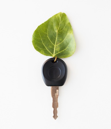 conservation, environment, transport and ecology concept - close up of car key and green leaf trinketの写真素材