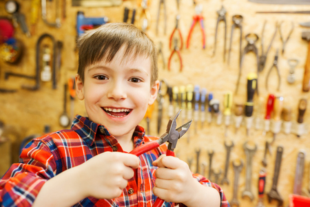 children, carpentry, profession and people concept - happy little boy with pliers at workshopの写真素材