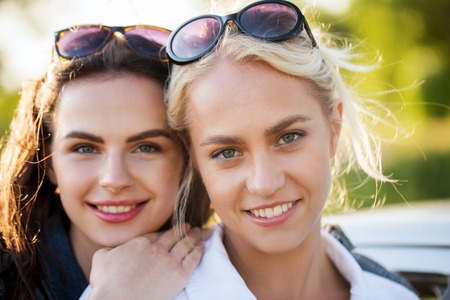 summer vacation, holidays, friendship and people concept - happy smiling young women or teenage girls outdoorsの写真素材
