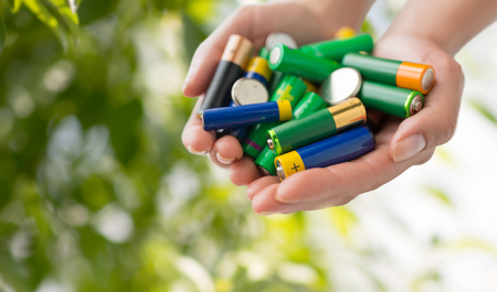 recycling, energy, power, environment and ecology concept - close up of hands holding alkaline...