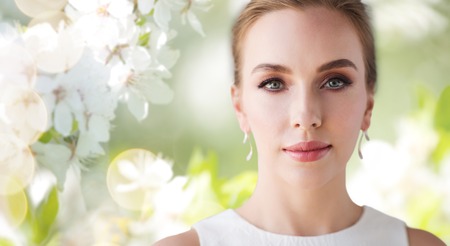 beauty, wedding and people concept - face of beautiful woman or bride in white dress over natural spring cherry blossom backgroundの写真素材