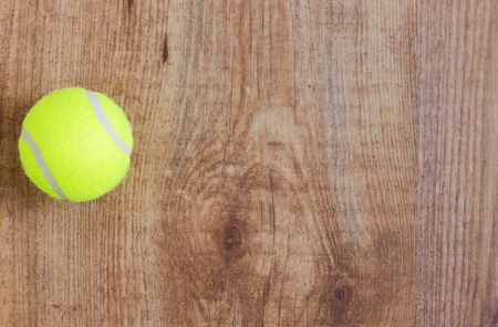 sport, fitness, game, sports equipment and objects concept - close up of tennis ball on wooden floor from topの写真素材