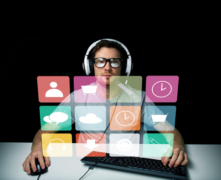 technology, media and people concept - young man or hacker in headset and eyeglasses sitting at...