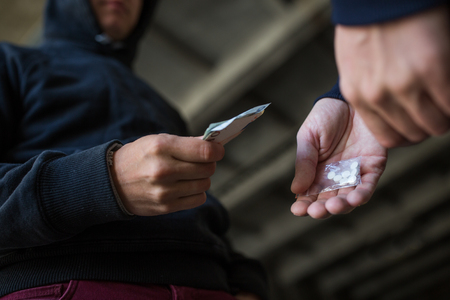 drug trafficking, crime, addiction and sale concept - close up of addict with money buying dose from dealer on streetの写真素材