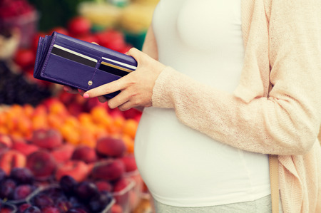 sale, shopping, pregnancy and people concept - close up of pregnant woman with wallet and and credit cards buying food at street marketの写真素材