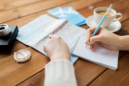 vacation, tourism, travel, destination and people concept - close up of traveler hands with blank notepad and pencilの写真素材
