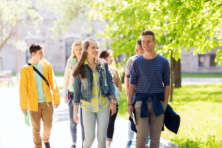 education, high school, communication and people concept - group of happy teenage students walking outdoorsの写真素材