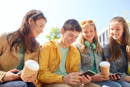 technology, internet and people concept - group of happy teenage friends with smartphone and coffee cups outdoorsの写真素材