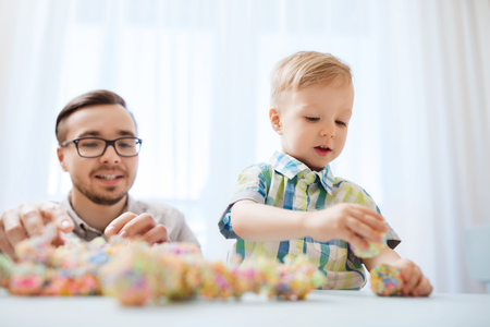 family, childhood, creativity, activity and people concept - happy father and little son playing with ball clay at homeの写真素材