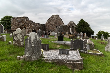 ancient monument and burial concept - old headstones and ruins on celtic cemetery graveyard in irelandの写真素材