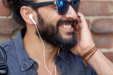 people, music, technology, leisure and lifestyle - hipster man with earphones and listening to music outdoorsの写真素材