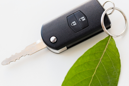 conservation, environment, transport and ecology concept - close up of car key and green leaf trinketの写真素材