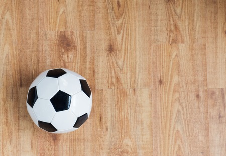 sport, soccer, football and sports equipment concept - close up of ball on wooden floor from topの写真素材