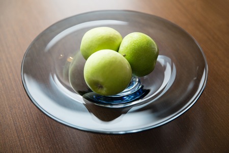 food, fruits, diet and healthy eating concept - close up of green apples on glass plateの写真素材