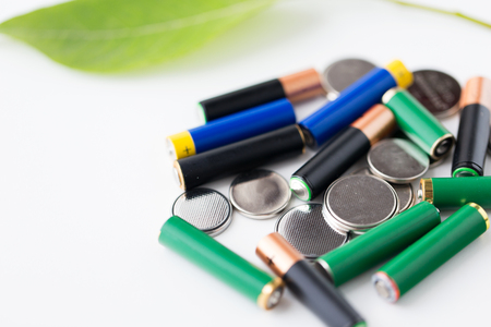 recycling, energy, power, environment and ecology concept - close up of green alkaline batteries and leafの写真素材