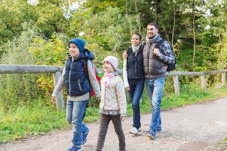 adventure, travel, tourism, hike and people concept - happy family walking with backpacks in woodsの写真素材