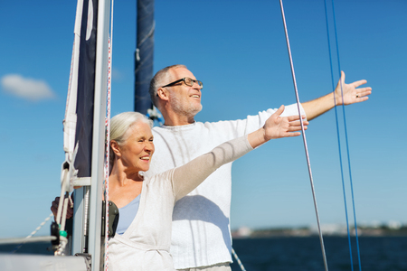 sailing, age, tourism, travel and people concept - happy senior couple hugging on sail boat or yacht deck floating in seaの写真素材