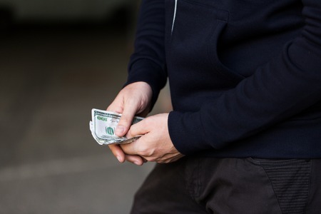 drug trafficking, finances, addiction, people and sale concept - close up of addict or dealer hands with dollar moneyの写真素材