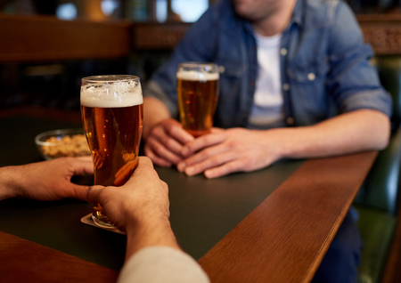 people, men, leisure, friendship and communication concept - close up of male friends drinking draft beer at bar or pubの写真素材