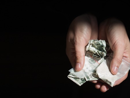 drug trafficking, crime, addiction and sale concept - close up of addict hands with drugs and moneyの写真素材