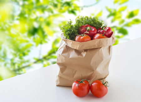cooking, diet, vegetarian food and healthy eating concept - paper bag with fresh ripe juicy vegetables and greens on table over green natural backgroundの写真素材