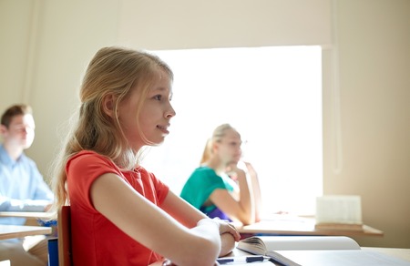 education, learning and people concept - happy student girl with book at school lessonの写真素材