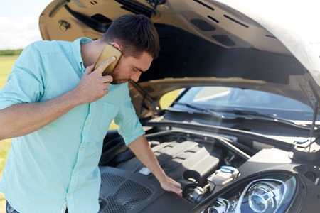 road trip, transport, travel, technology and people concept - young man with smartphone and open...