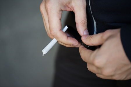 drug use, substance abuse, addiction, people and smoking concept - close up of addict hands with marijuana joint and lighterの写真素材