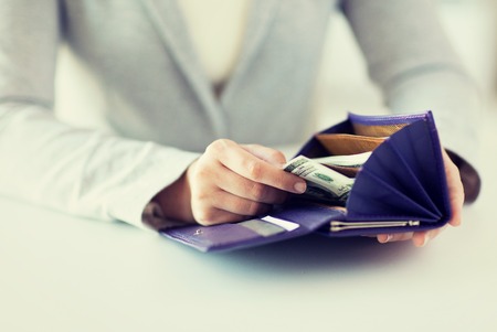 business, finance, saving, banking and people concept - close up of woman hands with wallet and us dollar moneyの写真素材