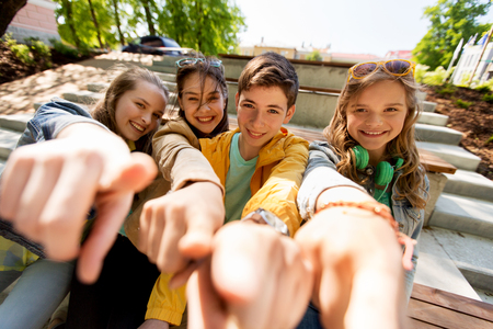 friendship, gesture and people concept - happy teenage friends or high school students pointing finger at youの写真素材