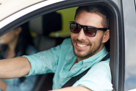 road trip, transport, travel and people concept - happy smiling man in sunglasses driving car
