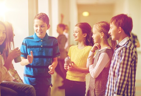 education, elementary school, drinks, children and people concept - group of school kids with soda cans talking in corridorの写真素材